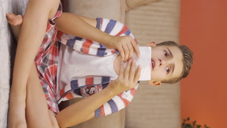 Vertical-video-of-Boy-covering-his-mouth-and-nose-with-a-tissue-while-coughing.